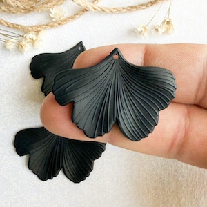 May include: Three black ginkgo leaf shaped polymer clay charms with a textured surface.