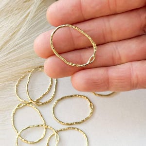 May include: A set of ten gold-toned oval rings with a textured finish. The rings are made of metal and are approximately 1 inch in diameter.