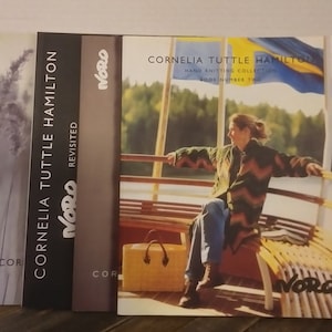 May include: Three books titled "Cornelia Tuttle Hamilton" with the word "Noro" on the cover. The books are stacked vertically. The front cover of the book on the right shows a woman sitting on a bench on a boat. The woman is wearing a brown and white striped sweater and blue jeans. The book cover has a blue and yellow flag in the background.