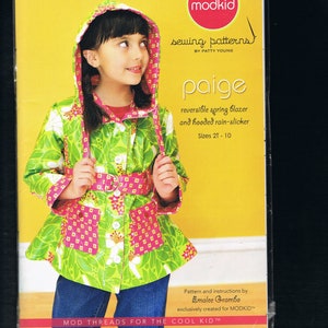 Op de afbeelding: Een naaipatroon voor een omkeerbare lenteblazer en een capuchon regenjas voor kinderen, maten 2T-10. Het patroon heet "Paige" en is van Patty Young. Het patroon is geïllustreerd met een jong meisje dat het afgewerkte kledingstuk draagt, dat groen en roze is met een bloemenprint.