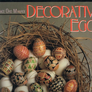 May include: A collection of decorated eggs in a nest of straw. The eggs are painted with various patterns and colours, including red, blue, green, and black. The title "Decorative Eggs" is visible at the top of the image.