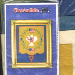 Puede incluir: Un kit de manualidades para una alfombra de fieltro con un tema patriótico. El kit incluye un patrón para una alfombra con una paloma, una corona de flores azules y dos banderas americanas. El kit también incluye el texto "#B-11 July Penny Rug "Independance Day"