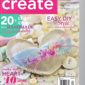 Op de afbeelding: Een tijdschriftcover met een handgemaakt hart van stof en knopen. Het tijdschrift heet "stitch craft create" en de tekst op de cover luidt "20+ Sweet Ideas for a Handmade Valentine's Day". Het tijdschrift is een knutselspecial en bevat eenvoudige DIY-stijlprojecten.
