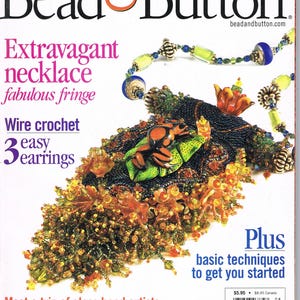 Puede incluir: Portada de la revista Bead & Button con un collar de cuentas de colores con un dije de rana verde y naranja. El texto de la portada de la revista dice "Collar extravagante, flecos fabulosos, Crochet de alambre, 3 aretes fáciles, Además técnicas básicas para empezar".