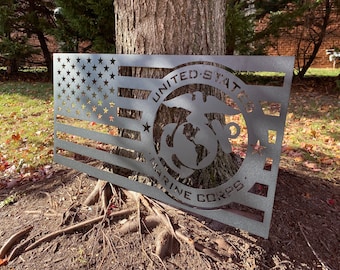May include: A metal cutout of the American flag with the United States Marine Corps emblem in the centre. The emblem is a globe with an eagle perched on top and the words "United States Marine Corps" surrounding it.