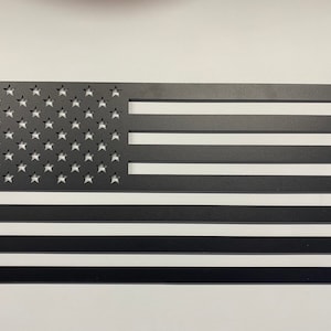 May include: A black metal cutout of the American flag. The stars are cut out of the metal, and the stripes are solid.