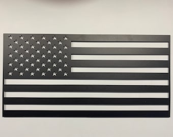 May include: A black metal cutout of the American flag. The stars are cut out of the metal, and the stripes are solid.