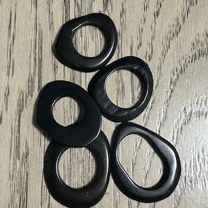 May include: Five black, smooth, rounded, ring-shaped pieces of wood.