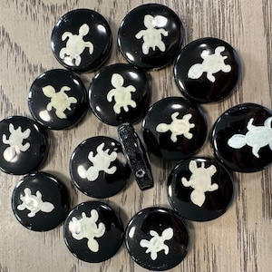 May include: A collection of 12 black and white round ceramic tiles with a white turtle design. Each tile has a different turtle design.