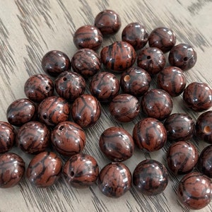 May include: A collection of brown and black patterned beads. The beads are round and have a smooth, glossy finish.