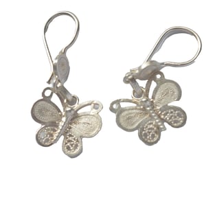 Puede incluir: Un par de pendientes de plata con forma de mariposa con delicados detalles de filigrana. Los pendientes tienen un cierre simple de gancho.