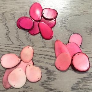 May include: Assortment of pink and red oval-shaped shell beads. The beads are smooth and have a natural, polished finish.