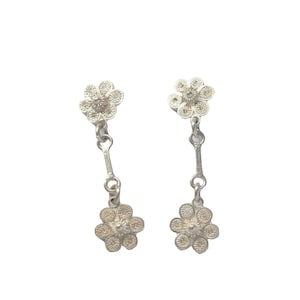 Puede incluir: Un par de pendientes de plata con dos delicados colgantes de flores en cada pendiente.