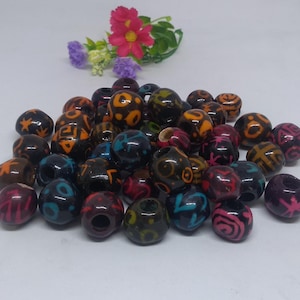May include: A collection of colorful wooden beads with intricate patterns. The beads are black, brown, orange, pink, blue, and green. They are perfect for making jewelry or other crafts.