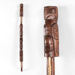 May include: A wooden totem pole with a carved eagle at the top. The pole is brown and has intricate carvings of other animals and figures.