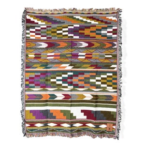 Puede incluir: Una manta tejida con un patrón geométrico en tonos de verde, naranja, morado, rojo y gris. La manta tiene un borde de flecos.