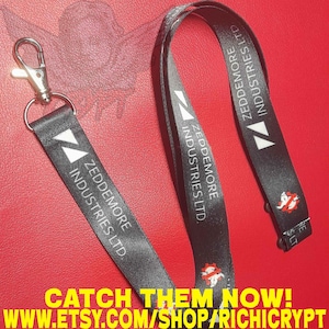 Könnte beinhalten: Schwarzes Schlüsselband mit weißem Text und silbernem Verschluss. Das Schlüsselband trägt den Text "ZEDDEMORE INDUSTRIES LTD" und ein Logo. Der untere Teil des Bildes enthält den Text "CATCH THEM NOW!" und eine Website-Adresse.