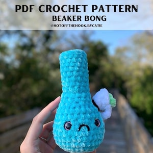 May include: A turquoise crochet beaker bong with a white and green accent. The bong has a sad face with black eyes and a curved mouth. The text "PDF CROCHET PATTERN BEAKER BONG @HOTOFFTHEHOOK.BYCATIE" is at the top of the image.