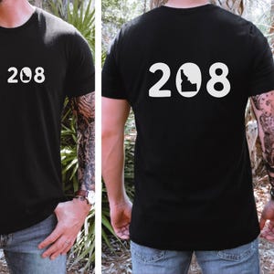 May include: Black crew neck t-shirt with the white number "208" printed on the front and back. The number "208" on the back is accompanied by a white outline of the state of Idaho.