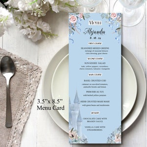 May include: A light blue menu card with a floral design and a castle illustration. The menu card is for a wedding reception and includes the date, "Alejandra", and a list of courses with descriptions. The card measures 3.5 inches by 8.5 inches.