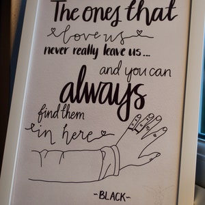 May include: A framed print with a black and white illustration of a hand reaching out with the text "The ones that love us never really leave us... and you can always find them in here" and the signature "~BLACK~" at the bottom.