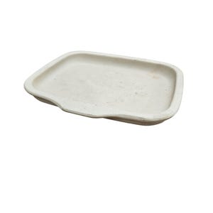 May include: A rectangular, off-white tray with a slightly irregular, wavy edge. The tray has a shallow depth and a smooth surface, suitable for serving or displaying small items. The neutral color and simple design make it versatile for various uses.