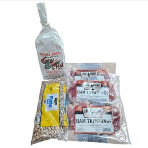May include: An assortment of food items, including a bag of Daniel Boone self-rising cornmeal mix, a bag of pinto beans, and several packages of Dan'l Boone Country Ham Trimmings. The cornmeal mix weighs 32 oz (2 lb).