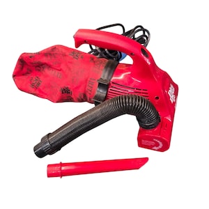 May include: A red handheld vacuum cleaner with a black flexible hose and a red dust bag. The vacuum has a red nozzle attachment and a black power cord. The words "Dirt Devil" are printed on the side of the vacuum.