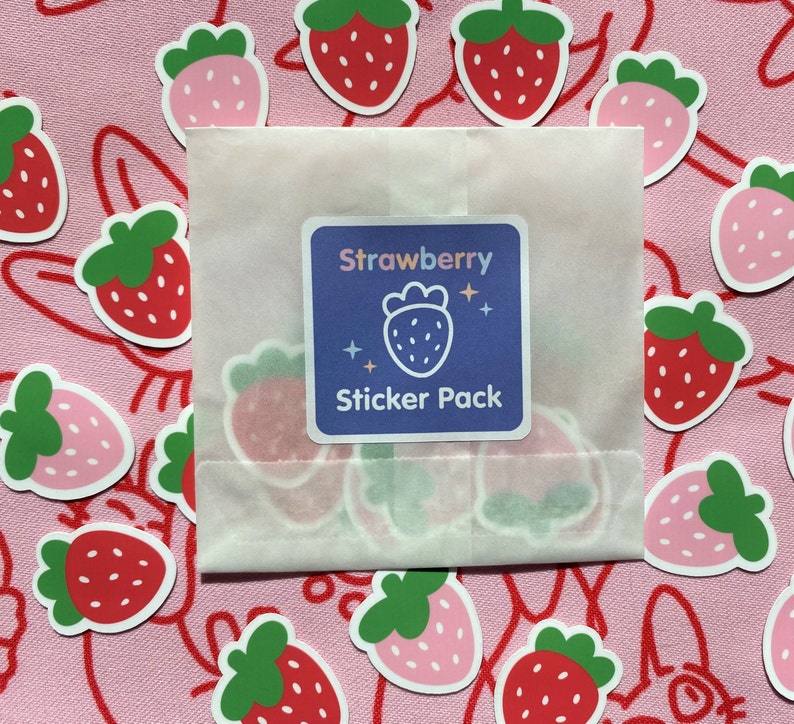 May include: A white envelope with a sticker pack of strawberry-themed stickers. The envelope has a sticker on the front that says "Strawberry Sticker Pack". The background is pink with a pattern of strawberries.
