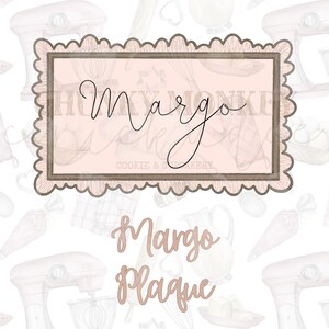 Puede incluir: Una placa decorativa rosa y marrón con el nombre "Margo" escrito en cursiva. La placa está rodeada por un borde festoneado y tiene un patrón de fondo de utensilios de cocina.