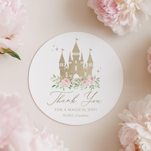 May include: A round white card with a gold castle illustration, pink flowers, and the text "Thank You FOR A MAGICAL DAY!" surrounded by pink peonies. The card also includes the text "XOXO, Caroline."