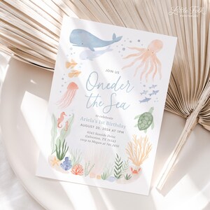 K&ouml;nnte beinhalten: Eine hellblaue und wei&szlig;e Einladung mit dem Text "Join Us Oneder the Sea" zur Feier des 1. Geburtstags von Ariela am 20. August 2024 um 13:00 Uhr. Die Einladung zeigt eine Aquarell-Illustration von Meerestieren, darunter ein Wal, ein Tintenfisch, eine Qualle, ein Seepferdchen, eine Schildkr&ouml;te und Fische.