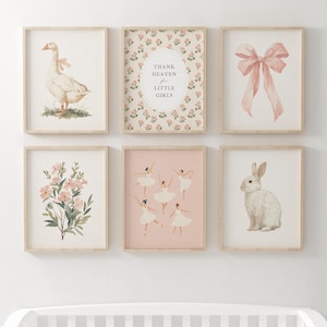 May include: A collection of six framed art prints with a nursery theme. The prints feature watercolor illustrations of a goose with a bow, a pink bow, flowers, ballerinas, a rabbit, and text that reads "Thank Heaven for Little Girls."