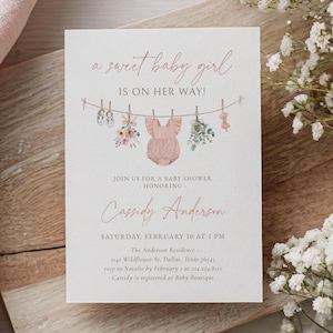 May include: A pink baby shower invitation with a watercolor illustration of a baby onesie, flowers, and baby shoes hanging on a clothesline. The text reads "a sweet baby girl is on her way!" and includes the details of the baby shower, including the date, time, location, and RSVP information.