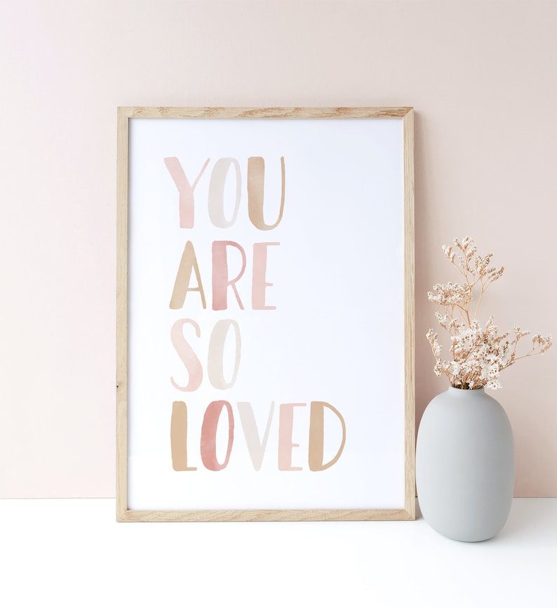 K&ouml;nnte beinhalten: Ein gerahmter Druck mit dem Text "YOU ARE SO LOVED" in rosa und braunen Aquarellbuchstaben auf wei&szlig;em Hintergrund.