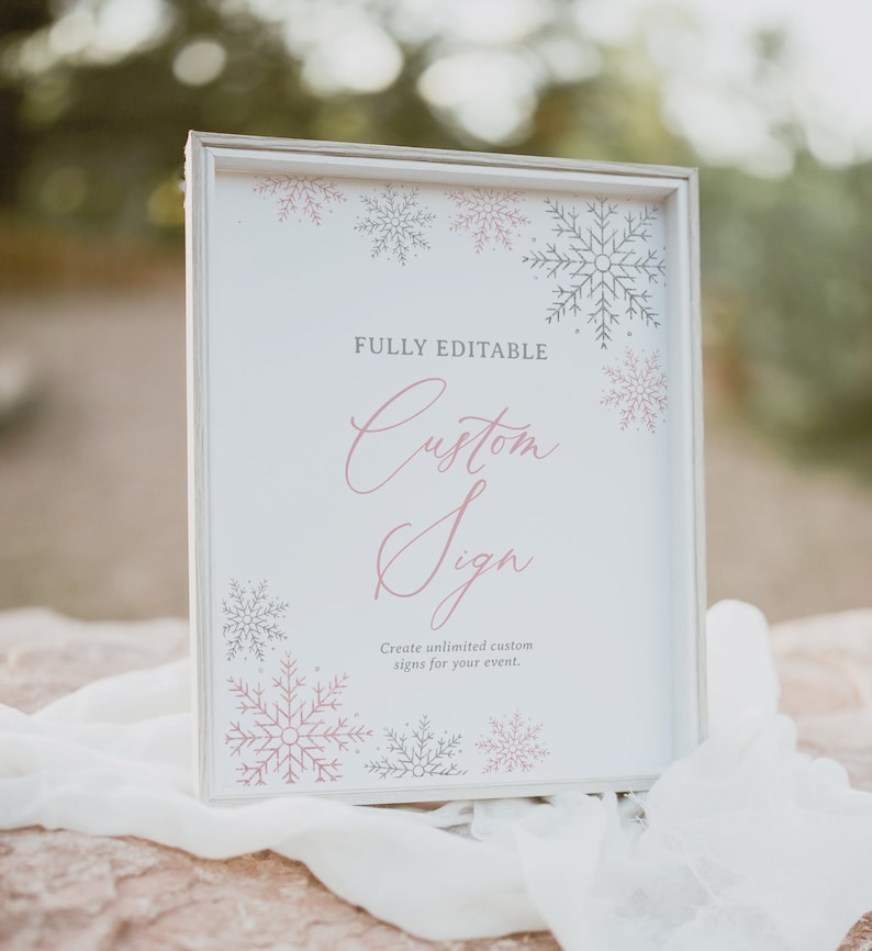 May include: A white sign with a wood frame and a pink and gray snowflake design. The sign says "FULLY EDITABLE Custom Sign Create unlimited custom signs for your event."