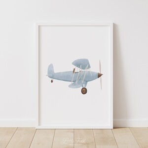 K&ouml;nnte beinhalten: Eine Aquarell-Illustration eines hellblauen Doppeldeckers mit braunem Propeller und R&auml;dern. Das Flugzeug fliegt vor einem wei&szlig;en Hintergrund.