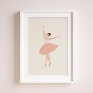 May include: A framed art print featuring a minimalist illustration of a ballerina. The dancer is depicted in a graceful pose, wearing a white leotard and a pink tutu. The artwork is set against a neutral background, framed in a white border.
