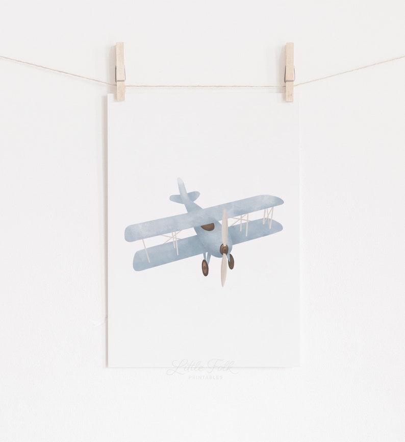 May include: A printable wall art design featuring a blue watercolor illustration of a vintage airplane with a brown propeller.