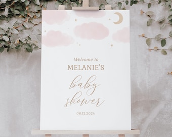 Puede incluir: Un cartel de bienvenida blanco con un diseño rosa y dorado con nubes, estrellas y una luna creciente. El texto dice "Bienvenido al Baby Shower de Melanie 06.12.2024".