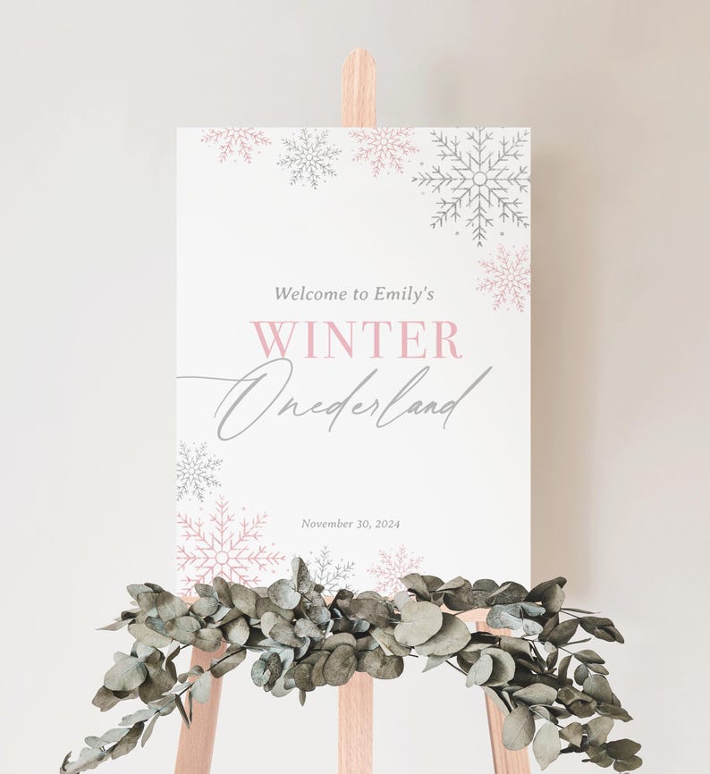 May include: A white sign with pink and grey snowflakes around the border. The sign says "Welcome to Emily's Winter Wonderland" with the date "November 30, 2024" below the text.