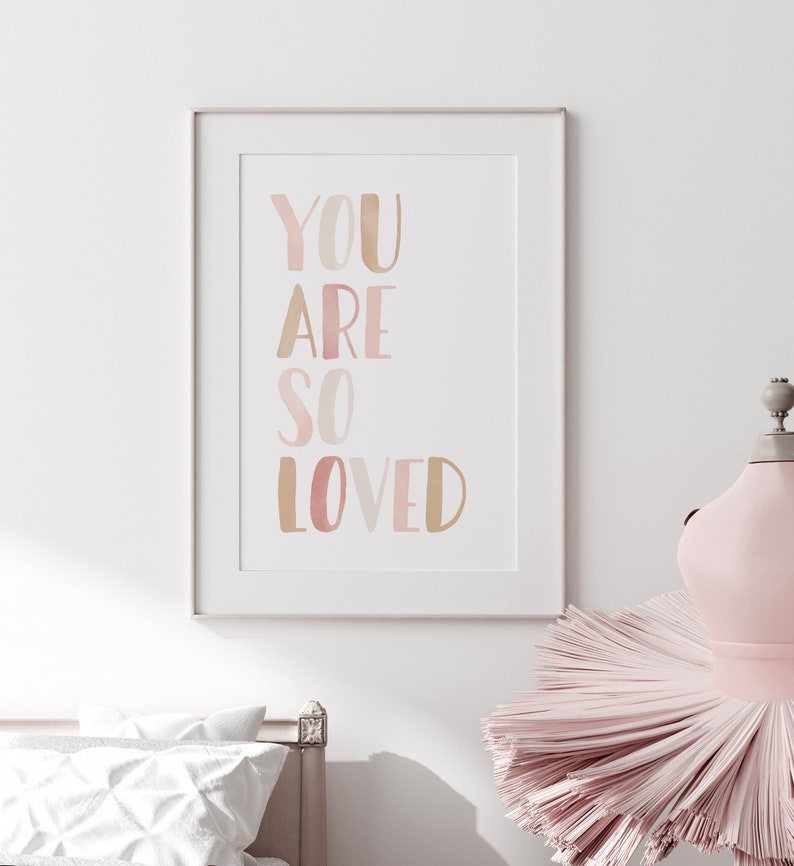 K&ouml;nnte beinhalten: Ein gerahmter Druck mit dem Text "YOU ARE SO LOVED" in Aquarell-Stil mit Ros&eacute;t&ouml;nen und Gold.