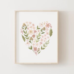May include: A framed watercolor painting of a heart shape made of pink, white, and green flowers. The flowers are arranged in a heart shape and are surrounded by green leaves.