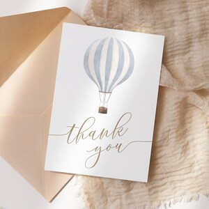 May include: A white card with a blue and white striped hot air balloon illustration and the text "thank you" in brown cursive writing.