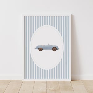 Pu&ograve; includere: Stampa incorniciata con un'illustrazione di un'auto cabriolet azzurra all'interno di un ovale bianco. Lo sfondo presenta strisce verticali blu e bianche. La stampa &egrave; in una cornice bianca.