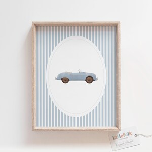 Pu&ograve; includere: Una stampa incorniciata con un'illustrazione di un'auto cabriolet azzurra all'interno di un ovale su uno sfondo a righe azzurro chiaro e medio. La cornice &egrave; di colore legno chiaro. La stampa &egrave; etichettata "littlefolk printables".