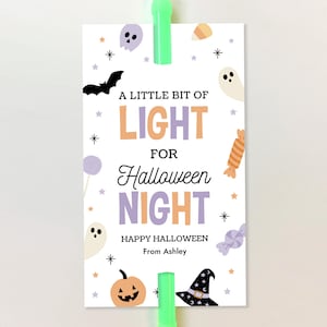 May include: A rectangular white tag featuring the text A LITTLE BIT OF LIGHT FOR Halloween NIGHT HAPPY HALLOWEEN From Ashley. The design includes illustrations of a black bat, ghosts, a pumpkin, a witch hat, candy, and stars in pastel colors.