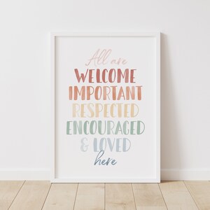 Könnte beinhalten: Ein weißer gerahmter Druck mit dem Text "All are WELCOME IMPORTANT RESPECTED ENCOURAGED & LOVED here" in einem Regenbogenfarbverlauf.