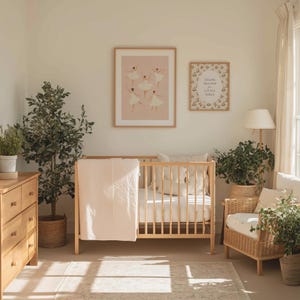 May include: A nursery scene with a light wood crib, dresser, and armchair. Two framed prints hang on the wall, one with ballerinas and the other with the text "THANK HEAVEN FOR LITTLE GIRLS". A pink blanket is draped over the crib.