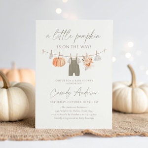 Peut inclure: Une invitation à une baby shower avec le texte "a little pumpkin is on the way!". Elle présente une guirlande avec une citrouille, une salopette et des éléments floraux. L'invitation est pour la baby shower de Cassidy Anderson, le 10 octobre.